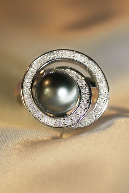 Packshot - Photographie d'une boucle d'oreille de luxe, avec perle centrale, sertie d'une spirale diamantée, sur tissu en soie